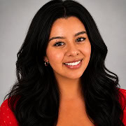 Woman with long dark hair smiles at the camera, wearing a red top and small hoop earrings, with a neutral gray background.